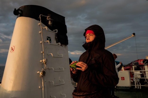 Una ragazza su una nave guarda attraverso il binocolo al tramonto