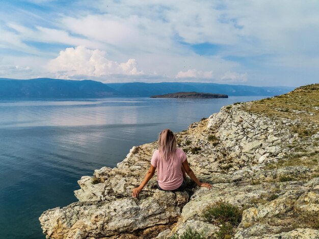 Una ragazza sul bordo di una scogliera sullo sfondo della regione del lago Baikal Irkutsk in Russia