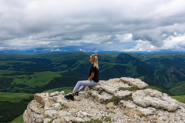 Una ragazza sulla scogliera dell'altopiano sullo sfondo del monte Elbrus Bermamyt