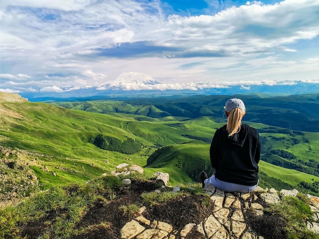 Una ragazza sulla scogliera dell'altopiano sullo sfondo del monte Elbrus Bermamyt