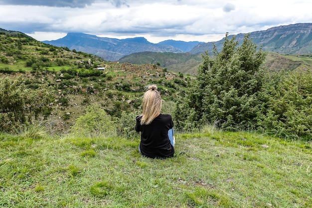 Una ragazza sullo sfondo del villaggio di Kurib nelle montagne del Caucaso sulla cima di una scogliera Daghestan Russia Giugno 2021