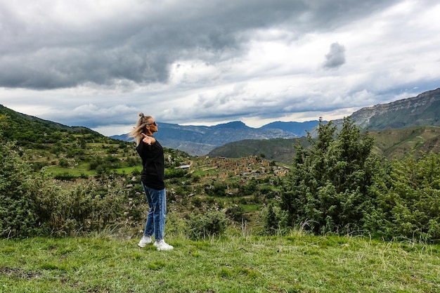 Una ragazza sullo sfondo del villaggio di Kurib nelle montagne del Caucaso sulla cima di una scogliera Daghestan Russia Giugno 2021