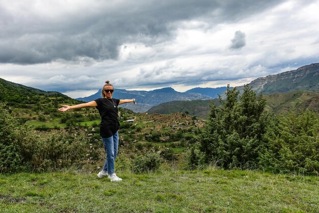 Una ragazza sullo sfondo del villaggio di Kurib nelle montagne del Caucaso sulla cima di una scogliera Daghestan Russia Giugno 2021