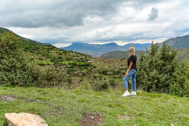 Una ragazza sullo sfondo del villaggio di Kurib nelle montagne del Caucaso sulla cima di una scogliera Daghestan Russia Giugno 2021