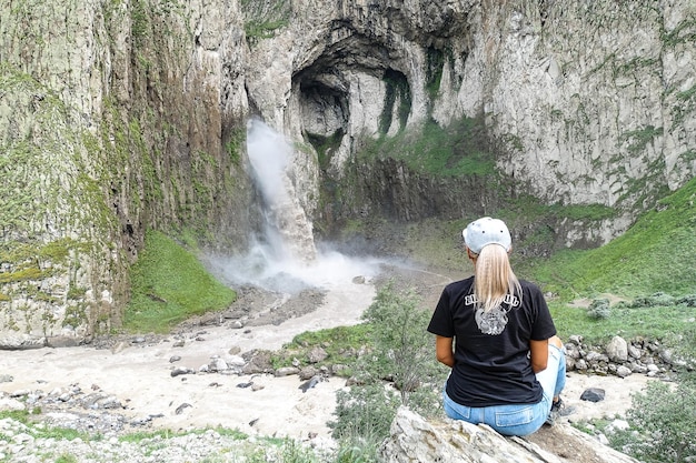 Una ragazza sullo sfondo della cascata TuzlukShapa sul territorio di KabardinoBalkaria Caucaso Russia