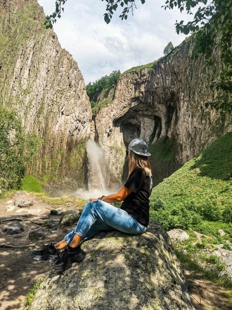 Una ragazza sullo sfondo della cascata TuzlukShapa sul territorio di KabardinoBalkaria Caucaso Russia