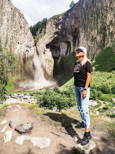 Una ragazza sullo sfondo della cascata TuzlukShapa sul territorio di KabardinoBalkaria Caucaso Russia