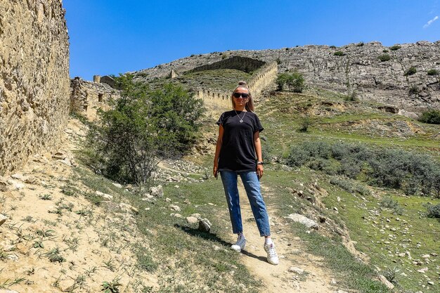 Una ragazza sullo sfondo della fortezza di Gunib Un muro protettivo Russia Daghestan giugno 2021