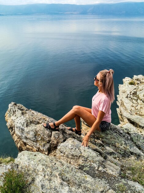 Una ragazza sullo sfondo di una vista del lago Baikal presso la roccia di Shamanka nella regione di Irkutsk in Russia