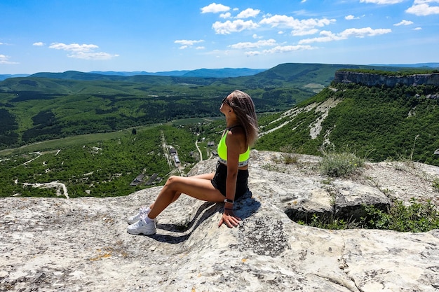 Una ragazza sullo sfondo di una vista delle montagne della Crimea dalla città rupestre di TepeKermen Maggio 2021 Crimea Russia