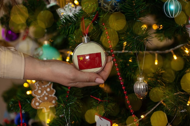 Una ragazza tiene una decorazione su un albero di Natale con la bandiera della Cina