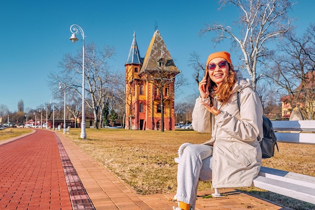 Una ragazza turistica felice che cammina lungo la riva del lago Palic in Serbia con una straordinaria architettura di torri e ville