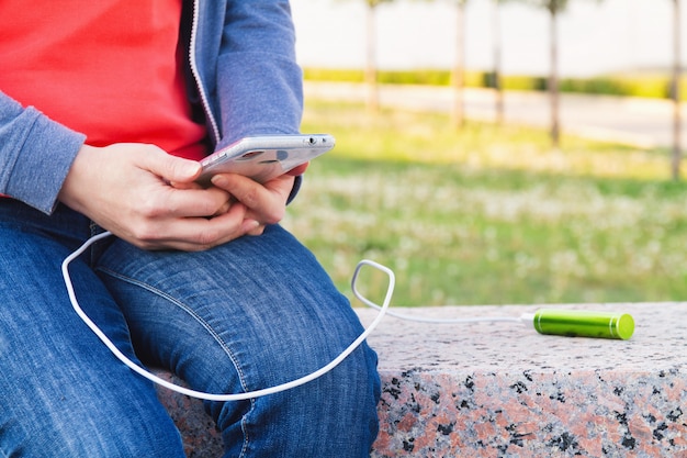 Una ragazza utilizza uno smartphone all'aperto mentre si carica da una banca di alimentazione esterna