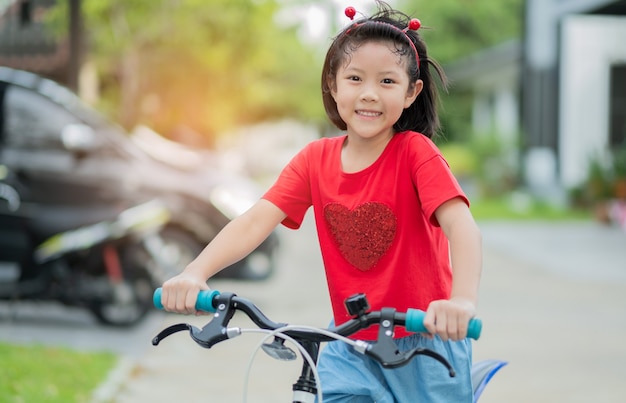 Una ragazza va in bicicletta, un bambino felice e sorridente, un bambino asiatico