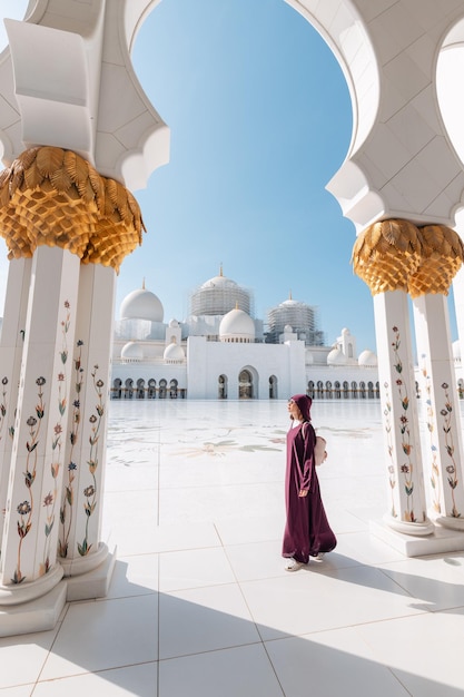 Una ragazza vestita con un'elegante abaya cammina graziosamente attraverso la grande moschea dello sceicco Zayed ad Abu Dhabi