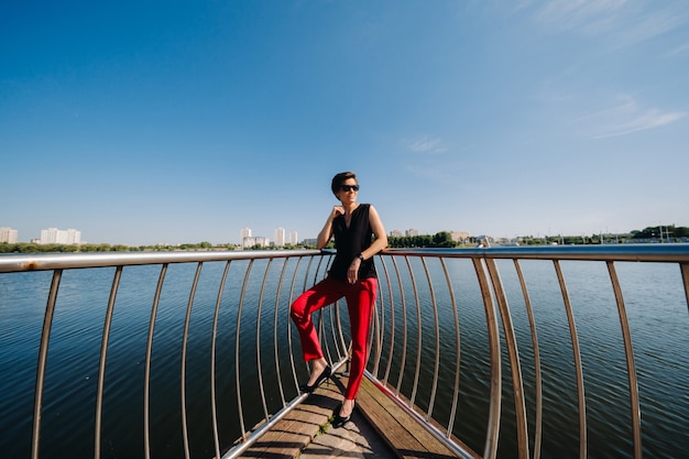 Una ragazza vestita di rosso sta su un molo vicino al lago
