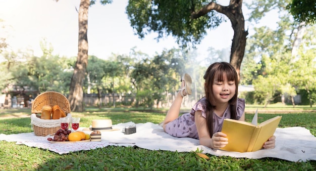 Una ragazzina asiatica carina legge un libro nel parco.