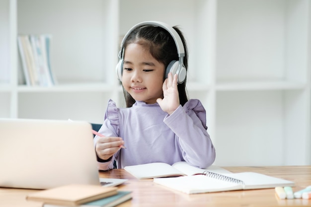 Una ragazzina che indossa le cuffie sta agitando la telecamera mentre è seduta a una scrivania