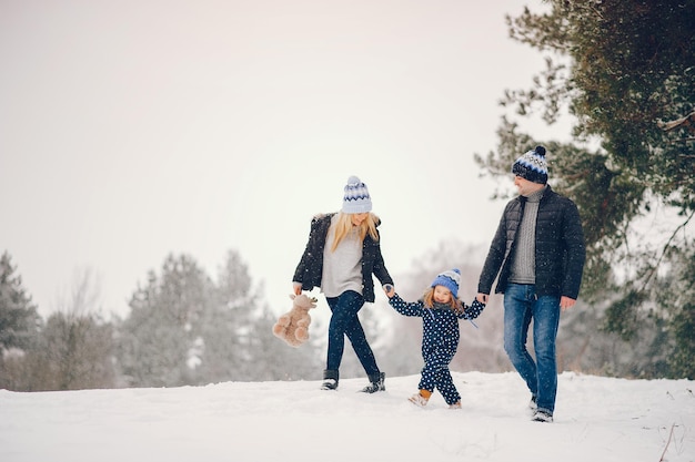 Una ragazzina con i genitori che giocano in un parco invernale