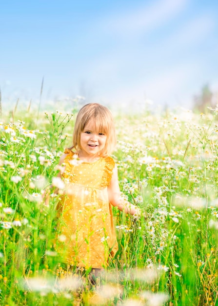 Una ragazzina con un vestito cammina in un campo di camomille