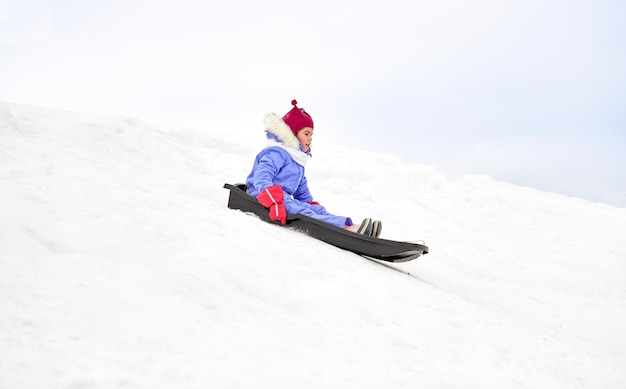 una ragazzina felice che scivola giù sulla slitta in inverno