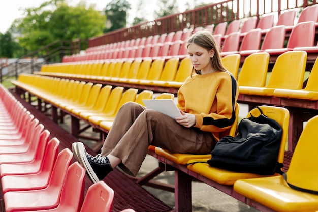 Una ragazzina sta facendo i compiti usando un portatile nelle tribune dello stadio