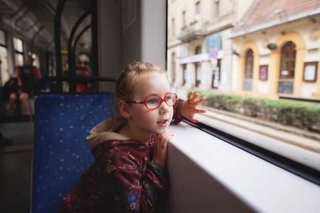Una ragazzina sta viaggiando su un tram e guarda con curiosità ai lati