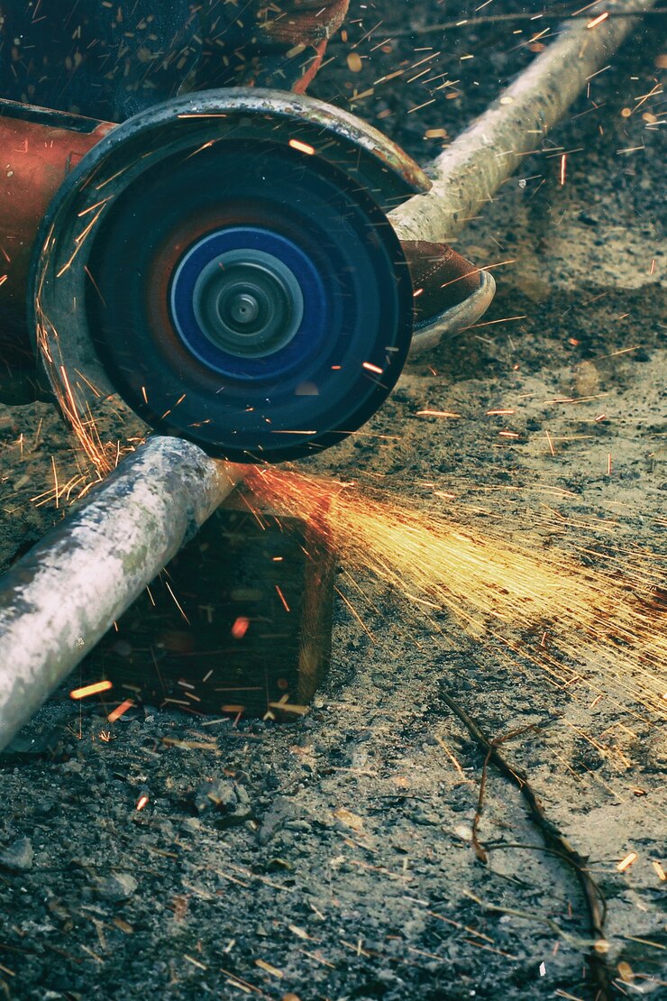 Una rettificatrice angolare che taglia un tubo metallico con un mazzo di spine.