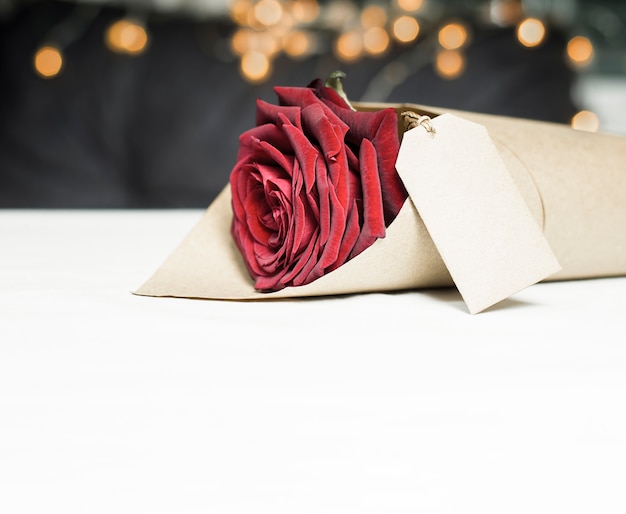 Una rosa rossa avvolta in carta da imballaggio con etichetta