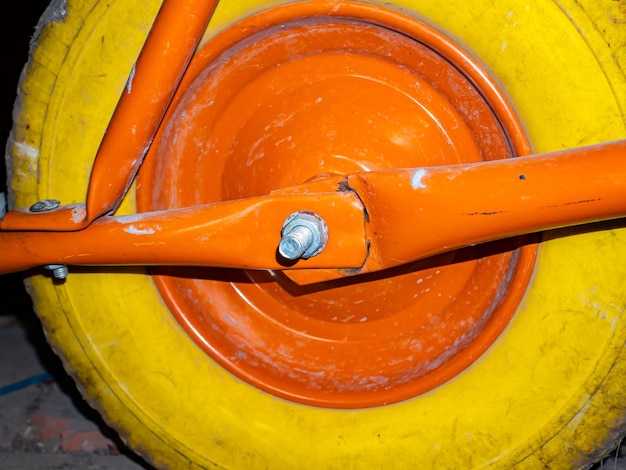 Una ruota gialla con un disco arancione di una carriola da giardino