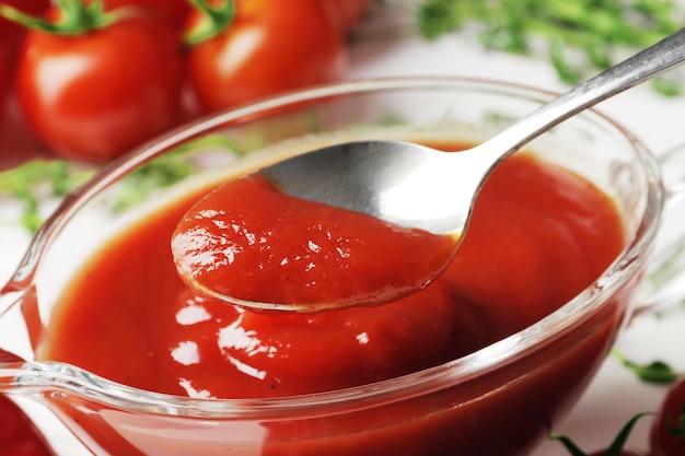 Una salsiera ripiena di deliziosa salsa di pomodoro un ramo di pomodorini freschi timo peperoncino fresco su uno sfondo di legno aglio fresco closeup