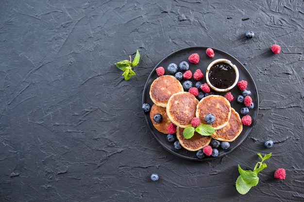 Una sana colazione a base di pancake al formaggio, frutti di bosco e miele. Decorazione d'atmosfera creativa