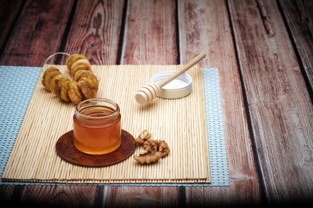 Una sana colazione con un dado di noce e frutta e miele biologico sullo sfondo del tavolo in legno.