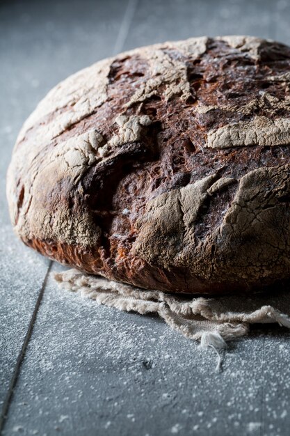 Una sana pagnotta di pane sulla tavola nera con farina