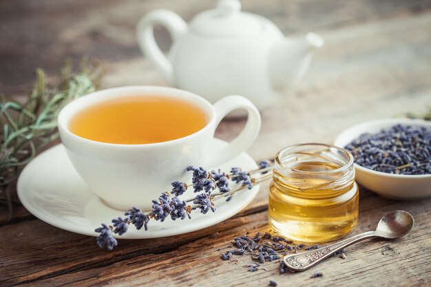 Una sana tazza di tè vasetto di miele secco fiori di lavanda e teiera sullo sfondo