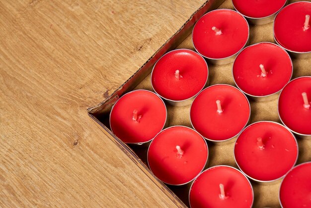 Una scatola di legno con dentro tante candele rosse