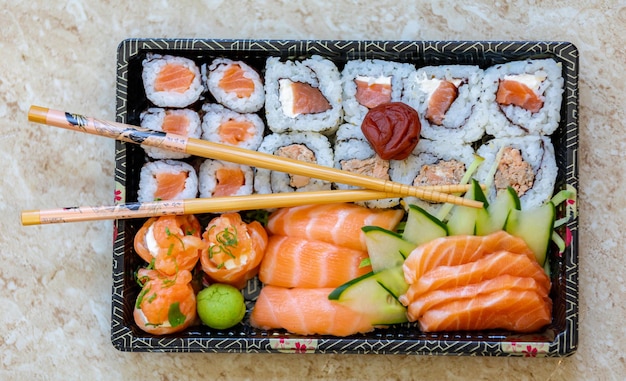 Una scatola di sushi con bacchette e un coltello.