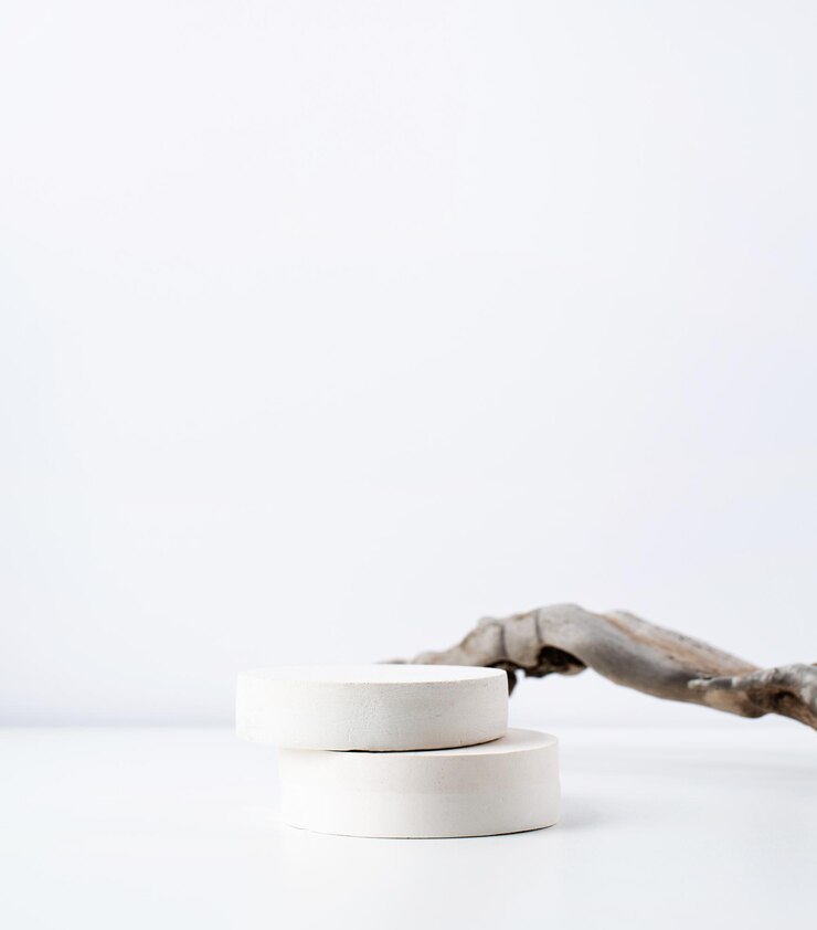 Una scena minimalista di un podio in gesso con pietre su sfondo bianco per cosmetici naturali