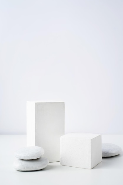 Una scena minimalista di un podio in gesso con pietre su sfondo bianco per cosmetici naturali