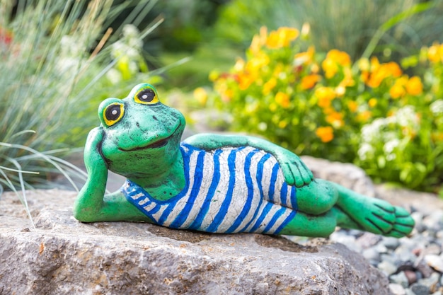 Una scultura da giardino di una rana sdraiata sul pavimento che legge un libro