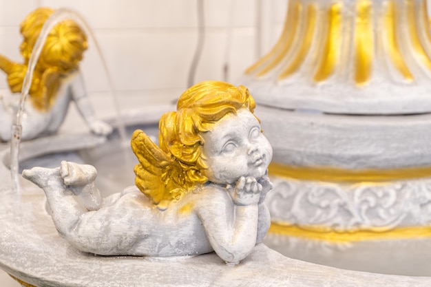 Una scultura di un bambino che ricorda un cupido dai capelli dorati che dorme in modo rilassato e sorridente una statua decorata da una fontana