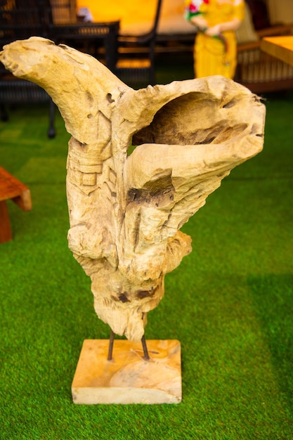 Una scultura di una donna con una gamba rotta è su un supporto di legno.