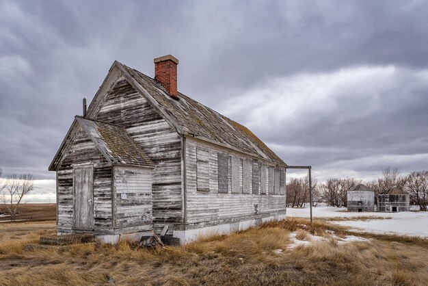 Una scuola abbandonata con bidoni del grano sullo sfondo nel Saskatchewan Canada