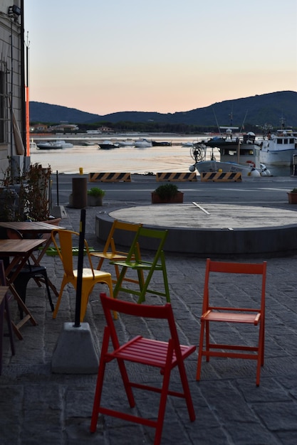 Una sedia colorata è nel patio di un ristorante del porto.