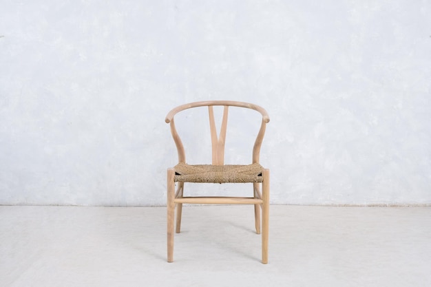 Una sedia con struttura in legno e un muro bianco dietro.