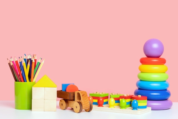 Una serie di giocattoli educativi per bambini su sfondo rosa Giocattoli in plastica e legno per lo sviluppo del pensiero e della logica