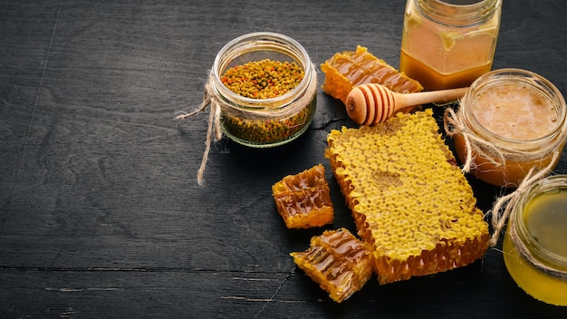 Una serie di prodotti a base di miele e api Miele in nido d'ape Su uno sfondo di legno nero Spazio libero per il testo Vista dall'alto