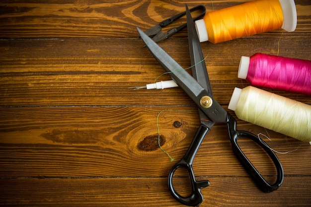 una serie di strumenti e fili per cucire vestiti su uno sfondo di legno