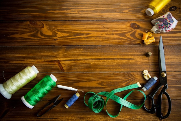 una serie di strumenti e fili per cucire vestiti su uno sfondo di legno