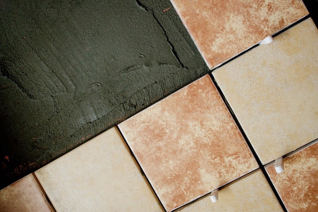 Una sezione di piastrelle marroni e crema appena posate sulla parete con guarnizioni in plastica Lavori di riparazione